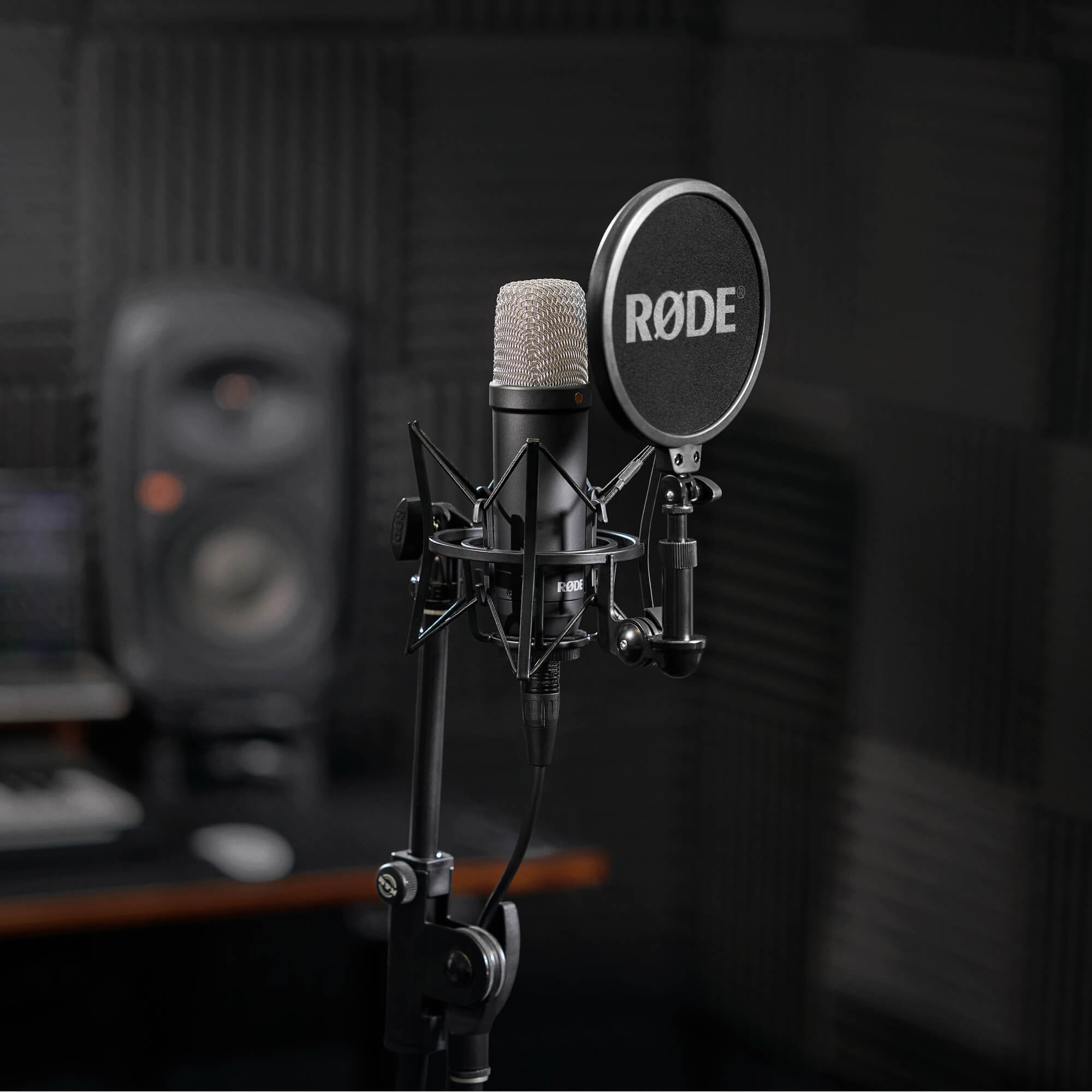 Røde NT1 microphone with pop filter, studio monitors in the background